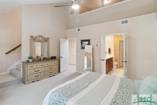 bedroom featuring light carpet, a high ceiling, ensuite bath, and baseboards