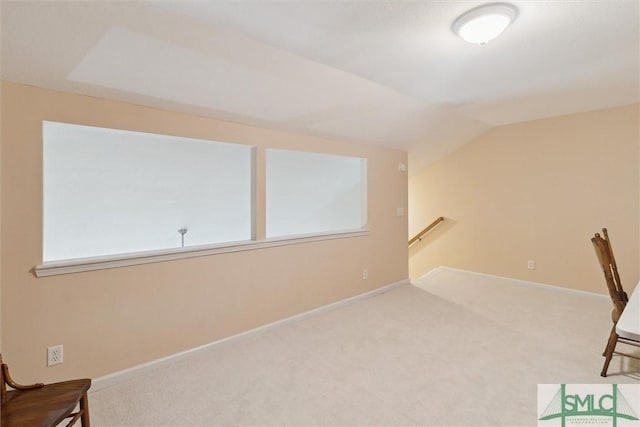 unfurnished room featuring vaulted ceiling, carpet floors, an upstairs landing, and baseboards