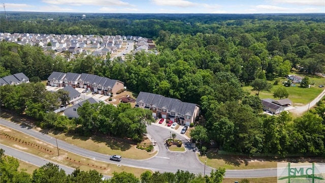 aerial view of property and surrounding area with a heavily wooded area and nearby suburban area