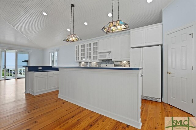 15 Teresa Ln, Tybee Island, GA 31328 - kitchen with white appliances, a center island, white cabinets, light wood-style flooring, and vaulted ceiling