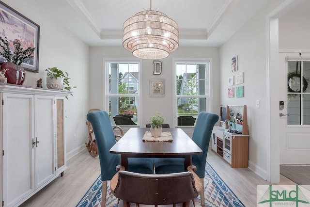 710 Longleaf Dr, Richmond Hill, GA 31324 - dining room with light wood-type flooring, ornamental molding, a tray ceiling, a chandelier, and baseboards