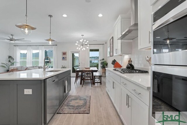 710 Longleaf Dr, Richmond Hill, GA 31324 - kitchen with appliances with stainless steel finishes, a sink, light countertops, light wood-style flooring, and wall chimney exhaust hood