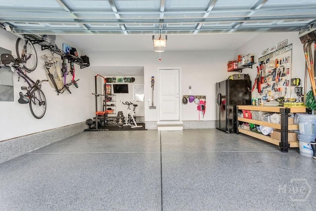 710 Longleaf Dr, Richmond Hill, GA 31324 - garage featuring a workshop area, black fridge with ice dispenser, and a garage door opener