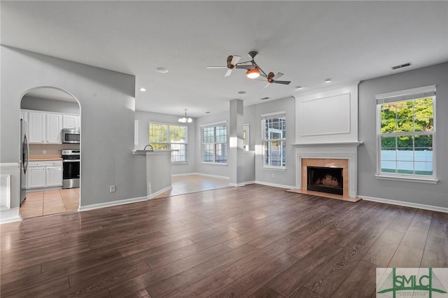 unfurnished living room with a ceiling fan, light wood-type flooring, a fireplace with raised hearth, baseboards, and recessed lighting