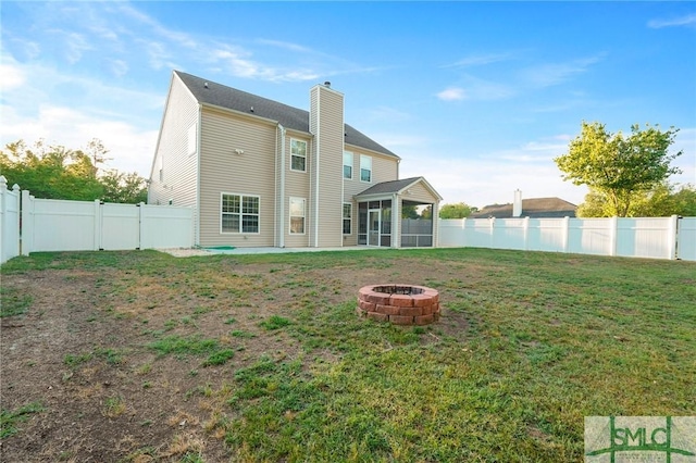 back of house with a fire pit, a chimney, a sunroom, and a patio area