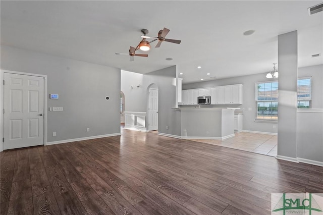 unfurnished living room featuring a ceiling fan, light wood finished floors, arched walkways, recessed lighting, and baseboards