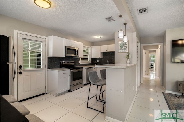 519 Screven Ave, Savannah, GA 31404 - kitchen featuring appliances with stainless steel finishes, a breakfast bar, light tile patterned flooring, a textured ceiling, and backsplash