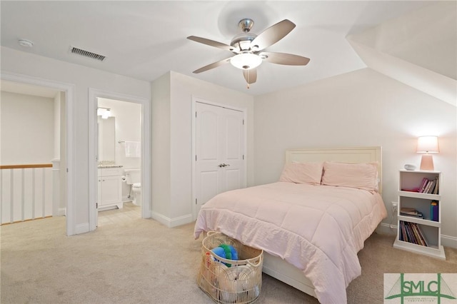 bedroom featuring light colored carpet, a ceiling fan, ensuite bath, and baseboards