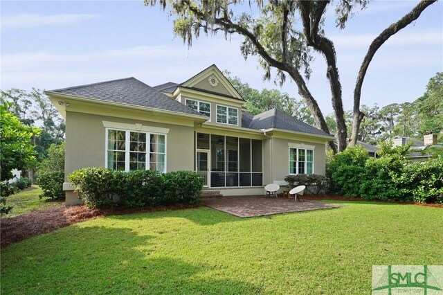 rear view of house featuring stucco siding, a yard, a patio, a shingled roof, and a sunroom