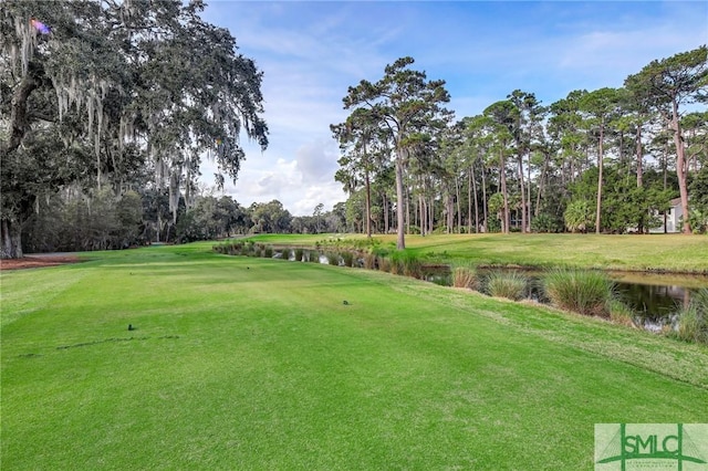 view of property's community featuring a water view, golf course view, view of wooded area, and a yard