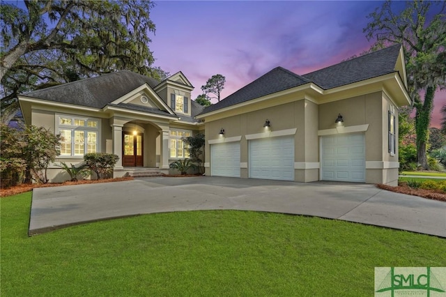 view of front facade with stucco siding, driveway, roof with shingles, and a front yard
