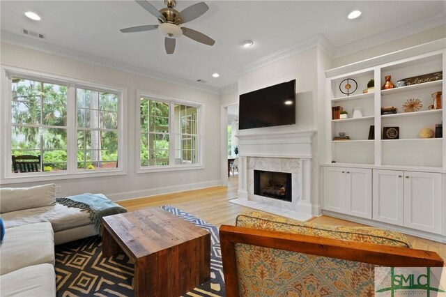 living area featuring ceiling fan, a fireplace, baseboards, ornamental molding, and recessed lighting