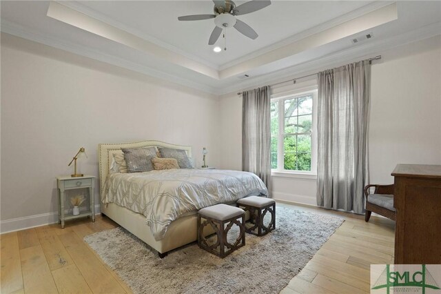bedroom with a raised ceiling, crown molding, light wood finished floors, baseboards, and recessed lighting