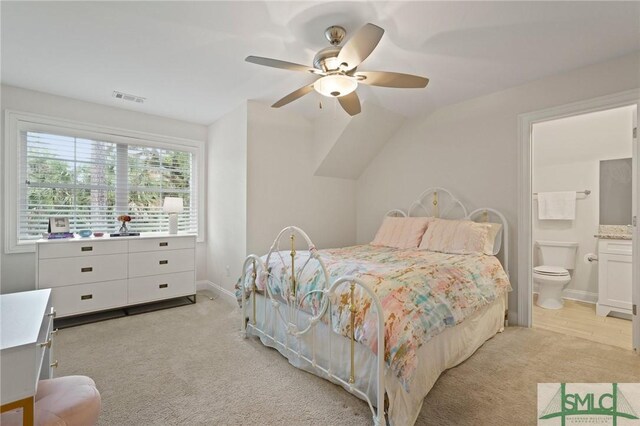 bedroom featuring light carpet, ensuite bathroom, baseboards, and a ceiling fan