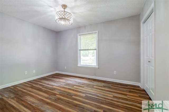1488 Old Augusta Rd, Clyo, GA 31303 - unfurnished bedroom featuring dark wood-type flooring, a closet, a chandelier, baseboards, and a textured ceiling