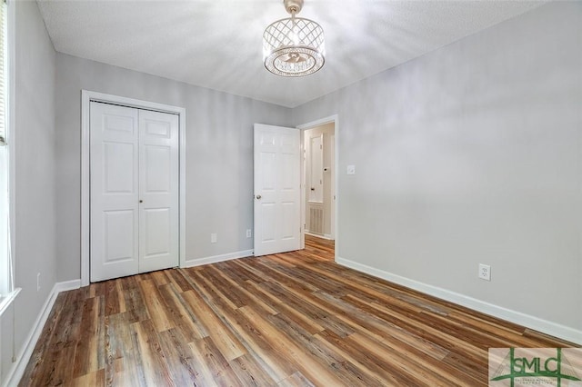 1488 Old Augusta Rd, Clyo, GA 31303 - unfurnished bedroom featuring a chandelier, wood finished floors, baseboards, and a closet