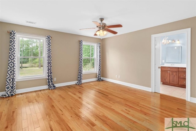 unfurnished room with light wood finished floors, baseboards, a ceiling fan, and a sink