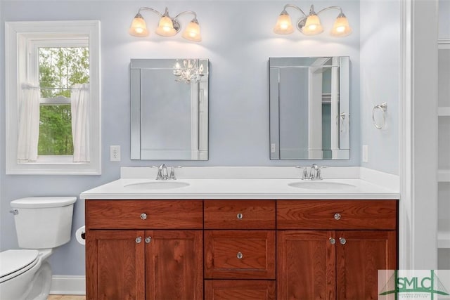 full bath featuring double vanity, toilet, and baseboards