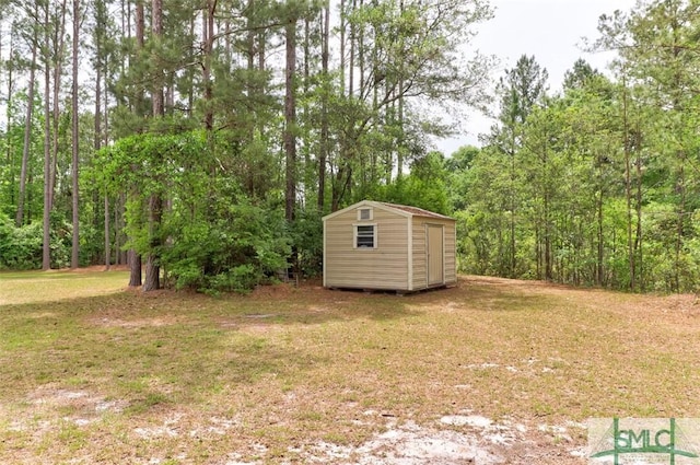 view of green lawn featuring a storage unit, an outdoor structure, and a view of trees