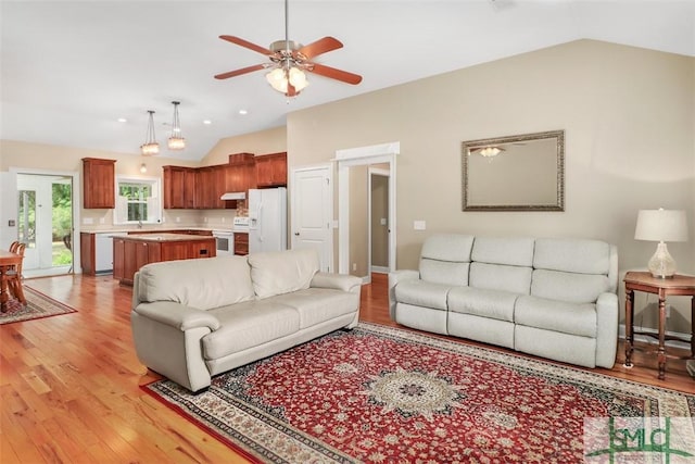 living area with lofted ceiling, light wood finished floors, and a ceiling fan