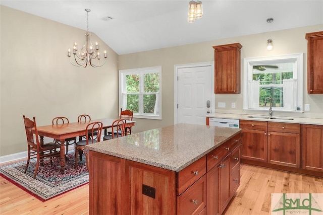 kitchen with a sink, light wood finished floors, a center island, white dishwasher, and brown cabinetry