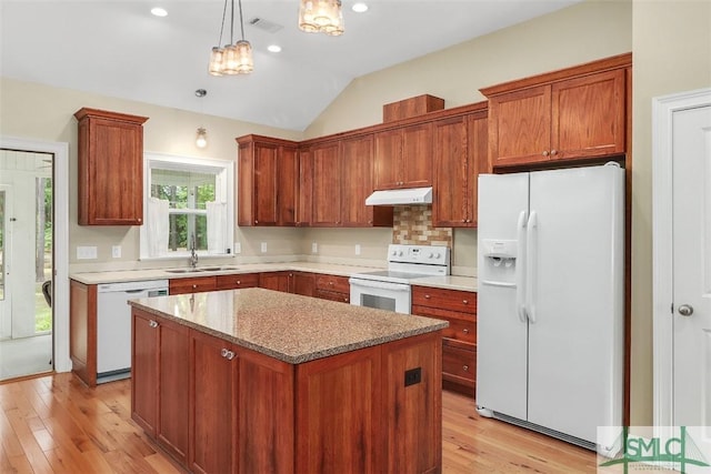 kitchen featuring white appliances, under cabinet range hood, a sink, lofted ceiling, and light wood finished floors