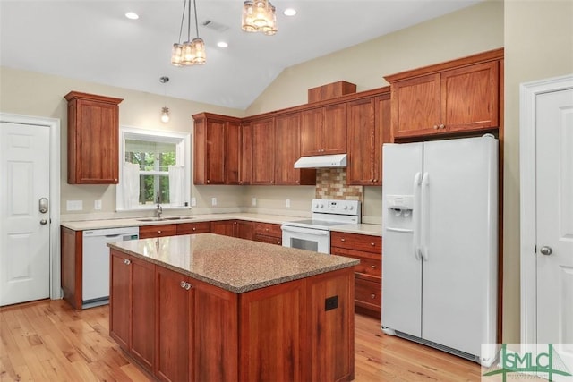 kitchen featuring white appliances, a sink, light wood finished floors, lofted ceiling, and a kitchen island