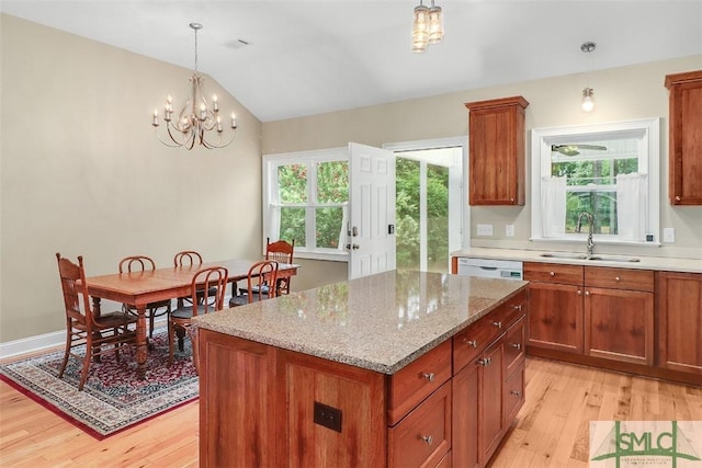 kitchen featuring a sink, light wood-style floors, a kitchen island, white dishwasher, and healthy amount of natural light