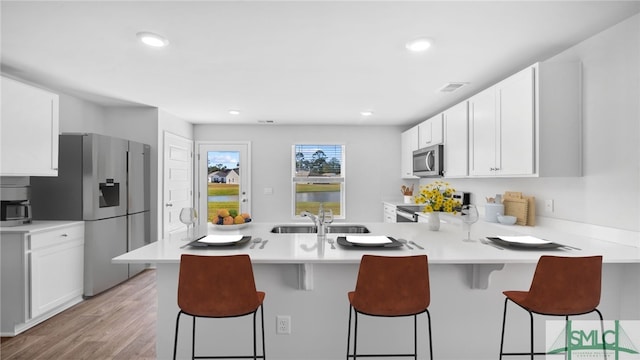 kitchen featuring appliances with stainless steel finishes, a sink, light countertops, white cabinets, and recessed lighting