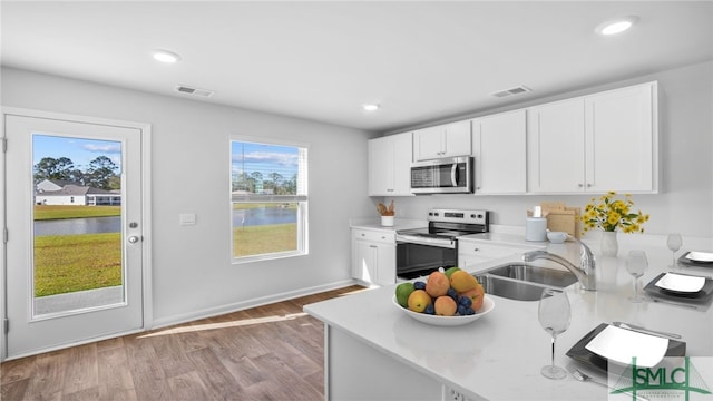 kitchen with stainless steel appliances, a sink, light countertops, white cabinetry, and recessed lighting