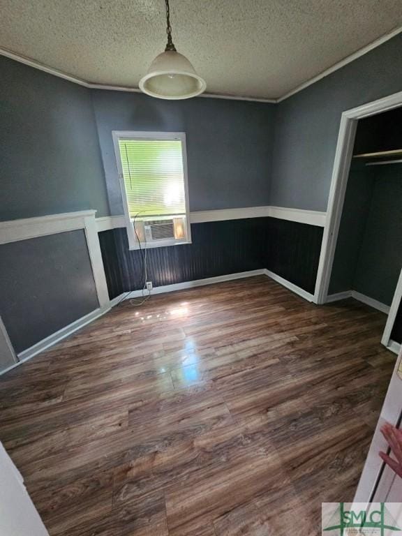 unfurnished dining area with wood finished floors, a textured ceiling, crown molding, and cooling unit