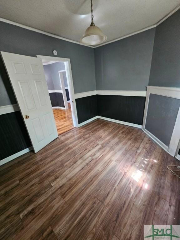 spare room featuring wood finished floors and crown molding