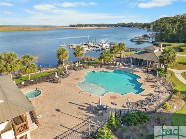community pool featuring fence, a water view, and a patio area