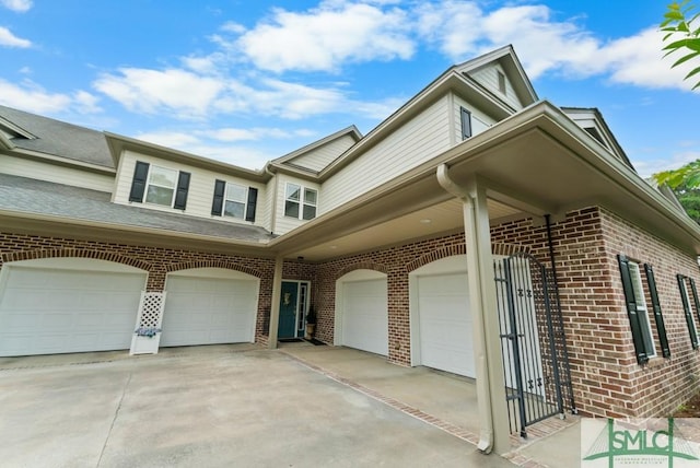 view of side of property featuring a garage, brick siding, and driveway