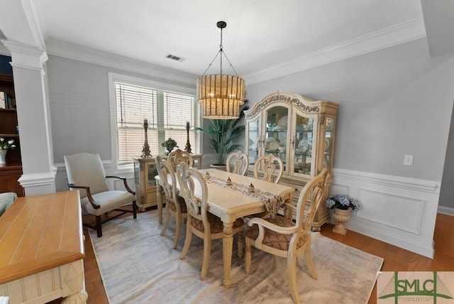 1104 River Oaks Dr Unit 1104, Richmond Hill, GA 31324 - dining space with decorative columns, a chandelier, light wood-style flooring, a wainscoted wall, and crown molding