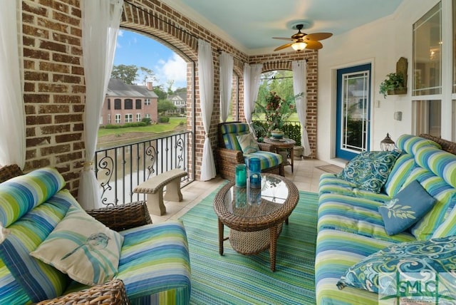 sunroom / solarium featuring a ceiling fan, tile patterned floors, and brick wall
