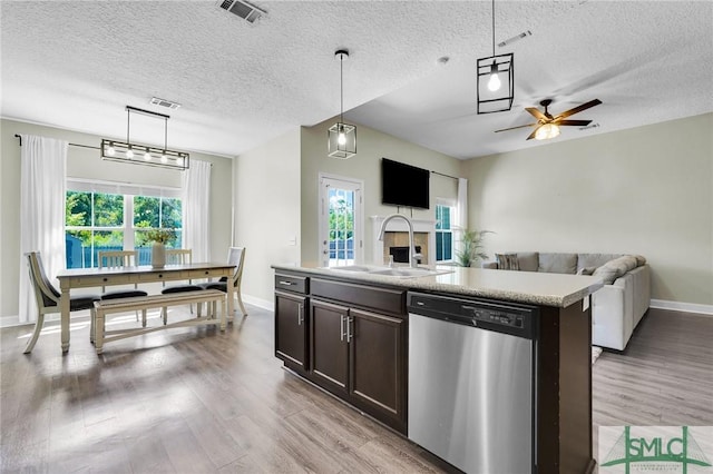 kitchen featuring dishwasher, a sink, a textured ceiling, light wood-style floors, and dark brown cabinetry