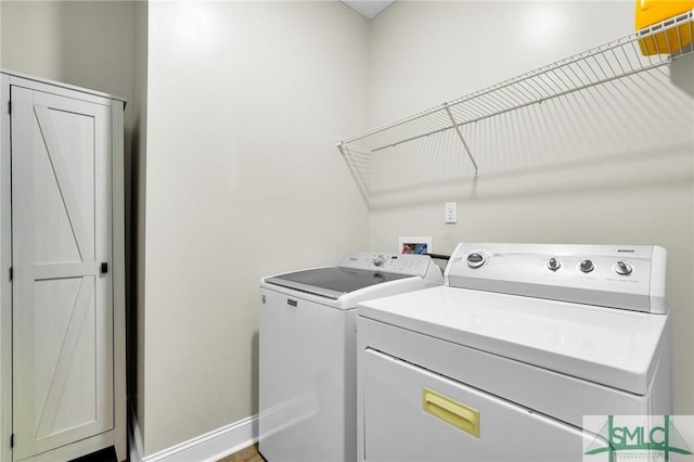 clothes washing area featuring washer and clothes dryer and baseboards