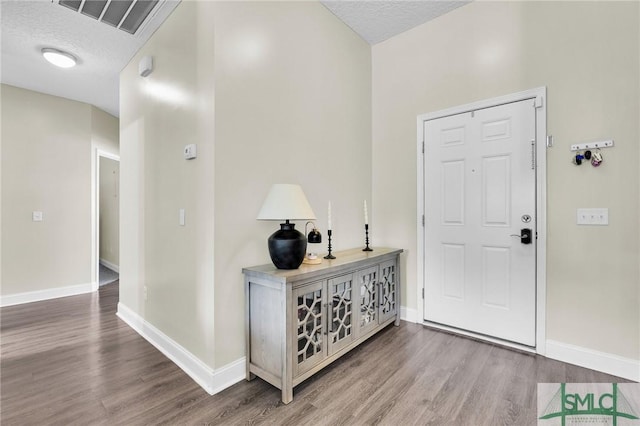 foyer with wood finished floors, baseboards, and a textured ceiling