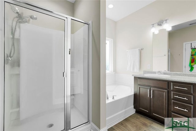 bathroom featuring a shower stall, a bath, vanity, and wood finished floors