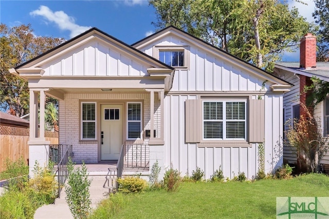 bungalow-style home with board and batten siding, a front lawn, a porch, and brick siding