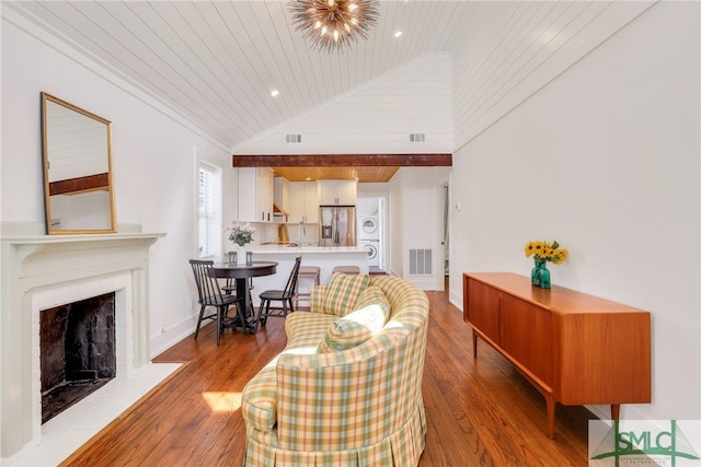 living room featuring lofted ceiling, wooden ceiling, wood finished floors, a fireplace with flush hearth, and ornamental molding