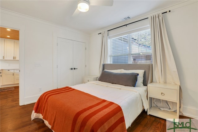 bedroom with dark wood-type flooring, crown molding, baseboards, a closet, and a ceiling fan