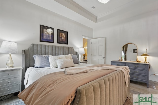 bedroom with ornamental molding, light wood-type flooring, and a tray ceiling