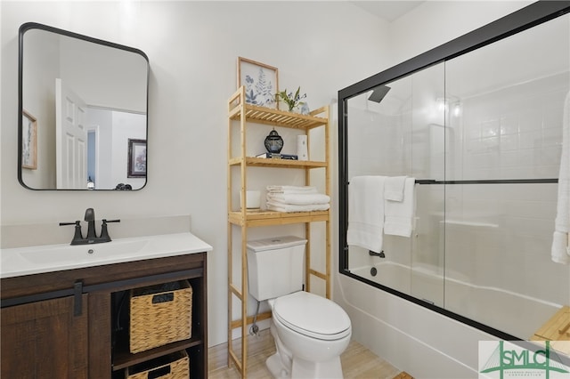 full bathroom with toilet, a sink, and bath / shower combo with glass door