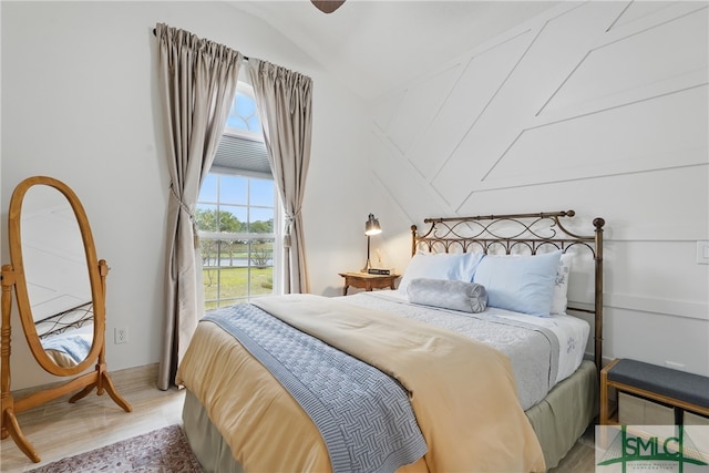 bedroom featuring lofted ceiling, multiple windows, and light wood-type flooring