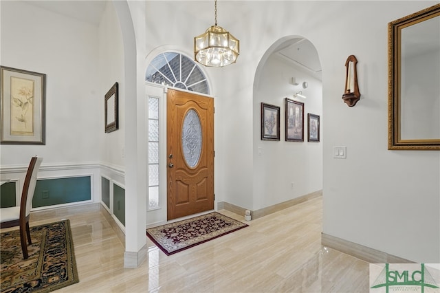 entryway with a chandelier, baseboards, and arched walkways