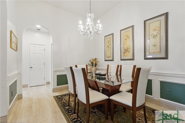 dining space with arched walkways and a chandelier