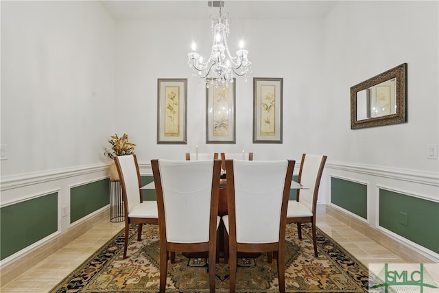 dining room featuring a chandelier, a decorative wall, and wainscoting