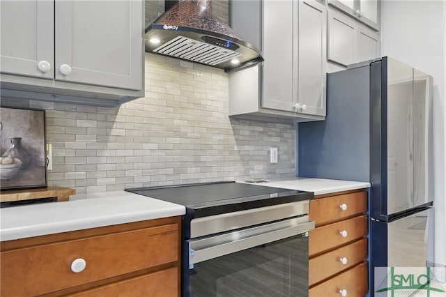 kitchen featuring wall chimney exhaust hood, appliances with stainless steel finishes, backsplash, and light countertops
